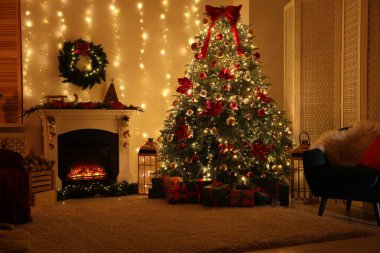 Güzel bir şömine, Noel ağacı ve karanlık odada şenlikli bir dekor. İç tasarım