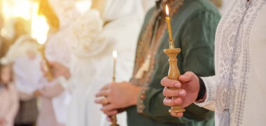 Kilisedeki vaftiz töreninde yanan mumları tutan insanlar, yakın çekim. Metin için boşluk