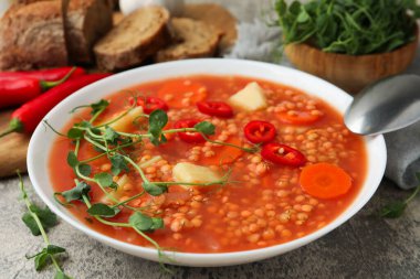 Gri masada servis edilen sebzeli lezzetli mercimek çorbası, yakın plan.