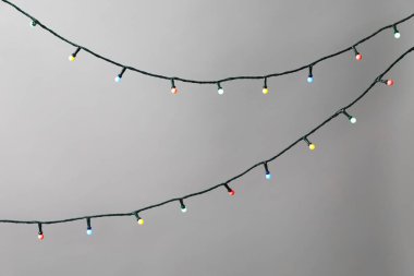 Gri arka planda parlak Noel ışıkları, yakın plan