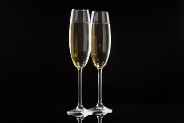 Siyah arka planda köpüklü şarap bardakları. Mutlu Noeller ve mutlu yıllar.