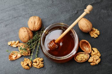 Cam kavanozda lezzetli bal, kepçe, ceviz ve kekik koyu dokulu masa, düz uzanma