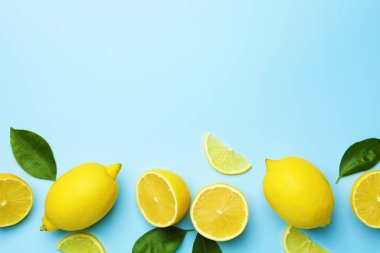 Taze limonlar ve açık mavi arka planda yapraklar, düz. Metin için boşluk