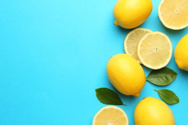 Taze limonlar ve açık mavi arka planda yapraklar, düz. Metin için boşluk