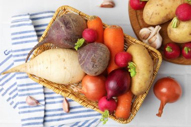 Beyaz fayanslı masada farklı çiğ sebzeler.