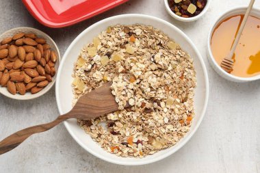 Tahıl yapıyorum. Bir kase yulaf ezmesi, bal ve kuru meyveler açık gri masada, düz yatıyordu.