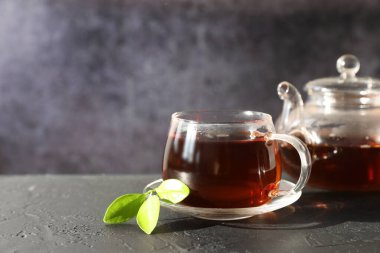 Sıcak çay fincanda ve çaydanlık siyah masada. Metin için boşluk