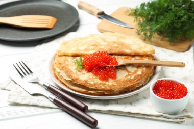 Kırmızı havyarlı leziz krepler ve beyaz ahşap masadaki dereotlar, yakın plan.