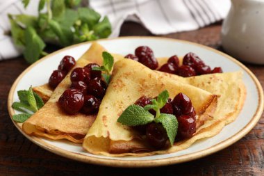 Tahta masada vişne reçeli ile servis edilen leziz krepler, yakın plan.