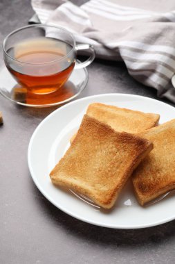 Taze kızarmış ekmek dilimleri. Gri masada çay ile servis edilir. Yakın plan.