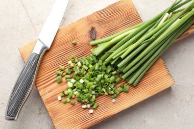 Açık gri masada yeşil soğan ve bıçak kes.