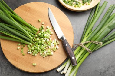 Yeşil soğan ve bıçak gri masada, düz yatıyordu.