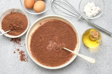 Çikolata hamuru, çırpı ve malzemeler gri desenli masada, düz yerde.