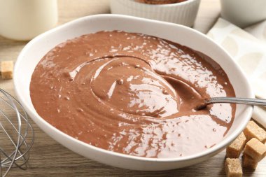 Kase içinde sıvı çikolata hamuru, ahşap masada çırpma ve esmer şeker, yakın plan.