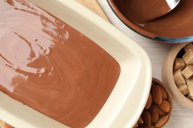 Sıvı çikolata hamuru, esmer şeker ve fındıklar ahşap masada, düz yatıyordu.
