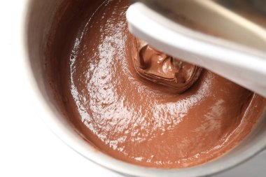 Beyaz masada kasede çikolata hamuru karıştırmak, üst manzara.