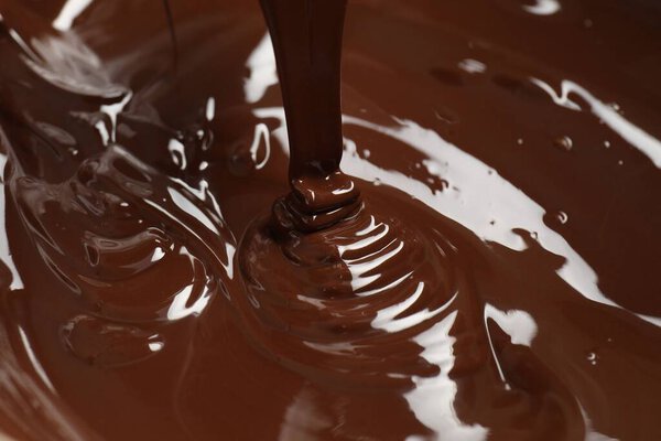 Tasty melted chocolate flowing down, closeup view