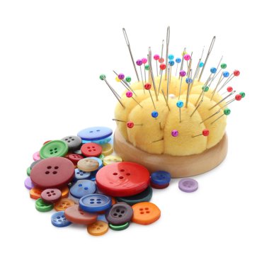 Beyaz üzerinde iğne, iğne ve düğme bulunan sarı iğneli iğne.