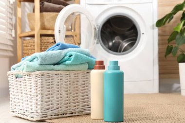 Çamaşır sepetinde havlular ve kapalı alanda deterjan şişeleri var.