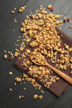 Kurutulmuş meyve ve siyah masada kaşık ile lezzetli granola, üst manzara.