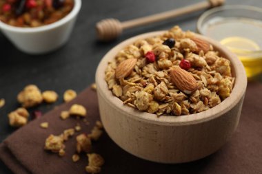 Lezzetli granola, kurutulmuş meyve, fındık ve bal, siyah masada, yakın plan. Metin için boşluk