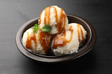 Karamel soslu lezzetli dondurma ve siyah masada nane şekeri.