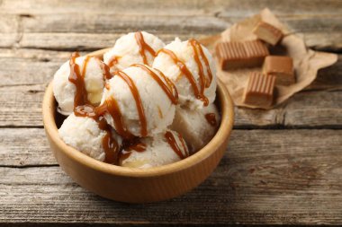 Tahta masadaki kasede karamel soslu lezzetli dondurma, yakın plan.