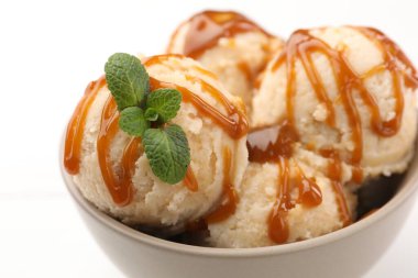 Karamel soslu lezzetli dondurma ve beyaz masada nane şekeri, yakın plan.