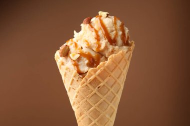 Karamel soslu lezzetli dondurma ve kahverengi arka planda badem.