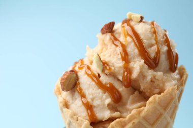 Karamel soslu lezzetli dondurma ve açık mavi arka planda badem, yakın plan. Metin için boşluk