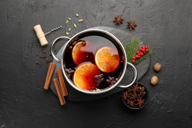 Çömlekte lezzetli şarap, tirbuşon ve siyah masada köknar dalları.