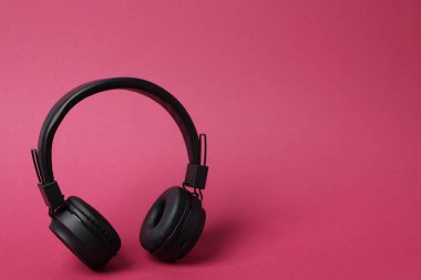 Pembe arka planda bir çift şık kulaklık. Metin için boşluk