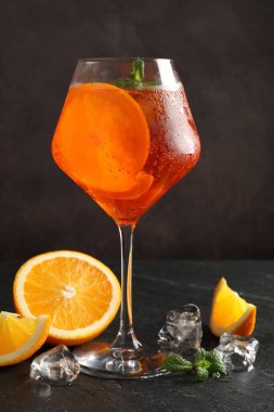 Bir bardak ferahlatıcı spritzer kokteyli. Nane, buz küpleri ve siyah masa üzerinde portakal dilimleri.