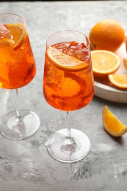 Gri desenli masaya serinletici spritzer kokteyli ve portakallar.