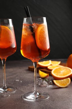 Gri masada serinletici spritzer kokteyli ve portakallar.