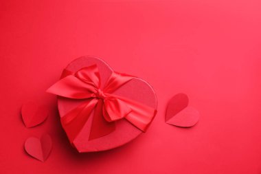 Sevgililer Günün kutlu olsun. Kalp şeklinde hediye kutusu ve kırmızı zemin üzerinde kağıt kalpler, düz yatıyordu. Metin için boşluk