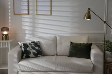 Rahat bir kanepe, lambalar ve ev bitkisi. İç tasarım