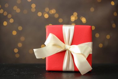 Gri arkaplanla siyah masada güzel bir hediye. Bokeh efektli, yakın plan. Metin için boşluk