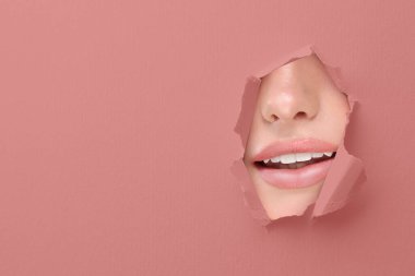 Güzel dudakları olan kadın, tozlu gül kağıdındaki yırtık delikten bakıyor.