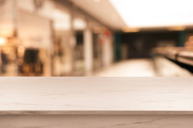 Bulanık alışveriş merkezi manzarasına karşı boş beyaz mermer masa. Tasarım için boşluk