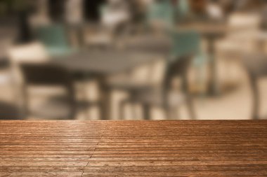 Boş ahşap masa, kafedeki bulanık masa ve sandalyelere karşı. Tasarım için boşluk