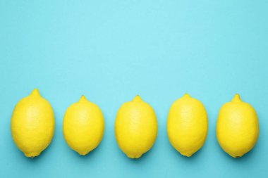 Açık mavi arka planda taze olgun limonlar, düz uzanmış. Metin için boşluk