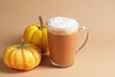 Cam bardakta kremalı balkabaklı latte ve bej arka planda taze sebzeler, yakın plan. Metin için boşluk