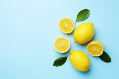 Taze limonlar ve açık mavi arka planda yapraklar, düz. Metin için boşluk