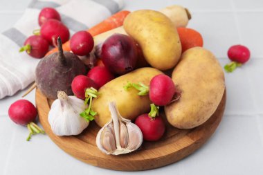 Beyaz fayanslı masada farklı çiğ sebzeler, yakın plan.