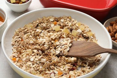 Tahıl yapıyorum. Bir kase yulaf ezmesi, bal ve kuru meyveler açık gri masada, yakın plan.