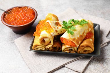 Kırmızı havyarlı lezzetli krepler, ekşi krema ve maydanoz gri masada, yakın plan.