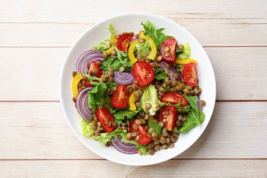 Hafif ahşap masada mercimek ve sebzeli nefis salata.