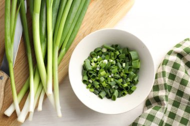 Taze taze soğan ve bıçak beyaz ahşap masada, düz yatıyordu.