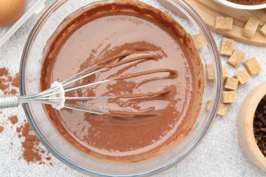 Kasede çırpılmış çikolata hamuru ve gri desenli masada baharatlar.